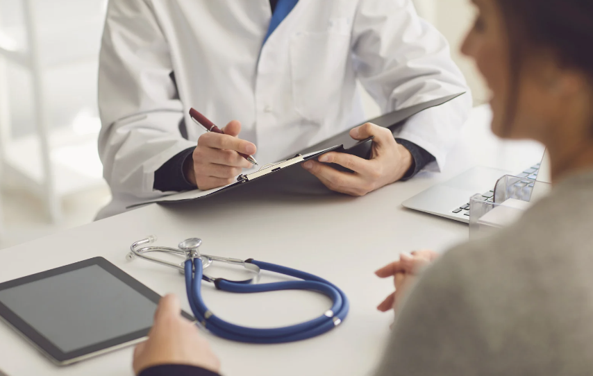 Doctor writing notes while meeting with a patient