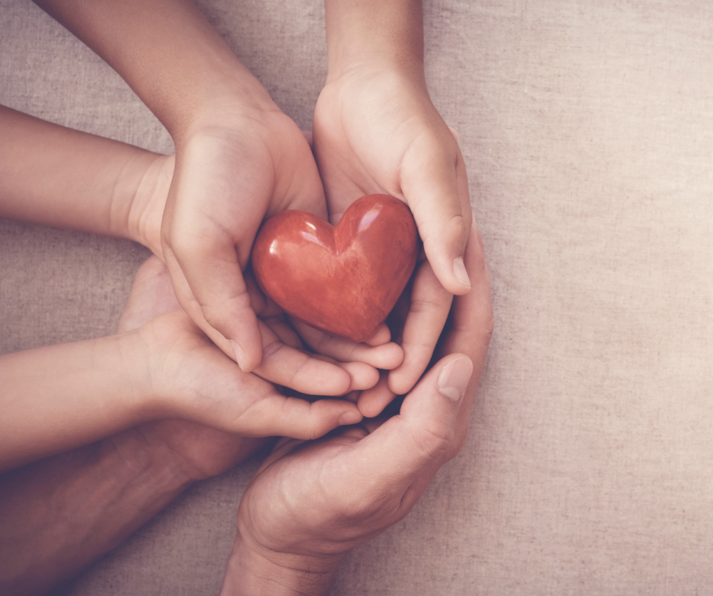 Family stacking hands with a heart stone