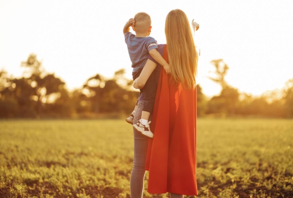 type 1 diabetes mom holding son wearing super hero cape