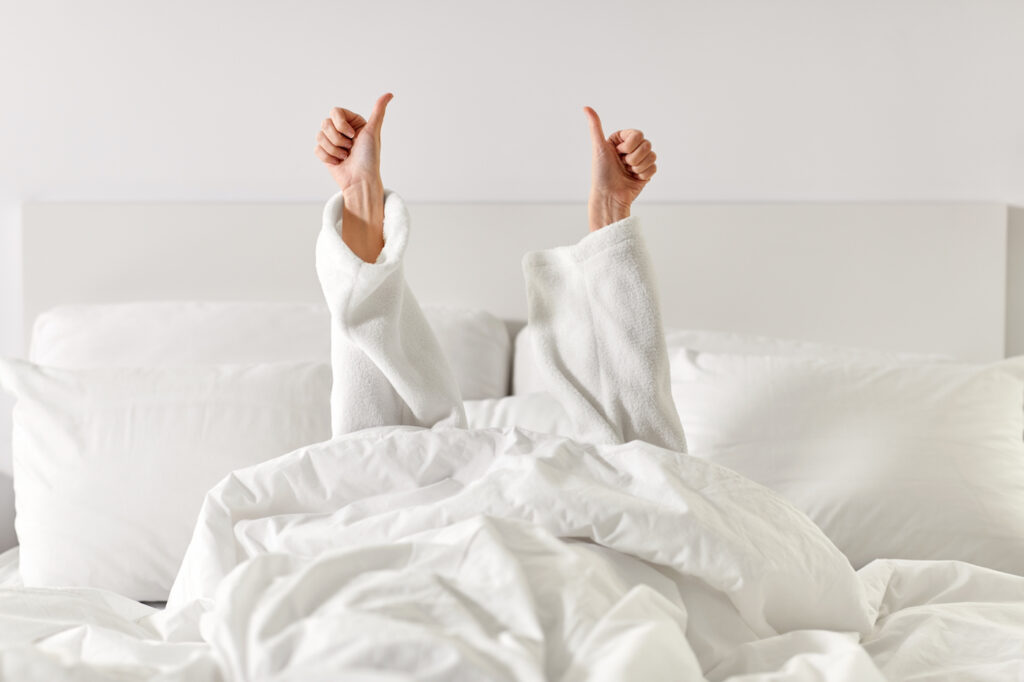 Woman laying in bed with thumbs up