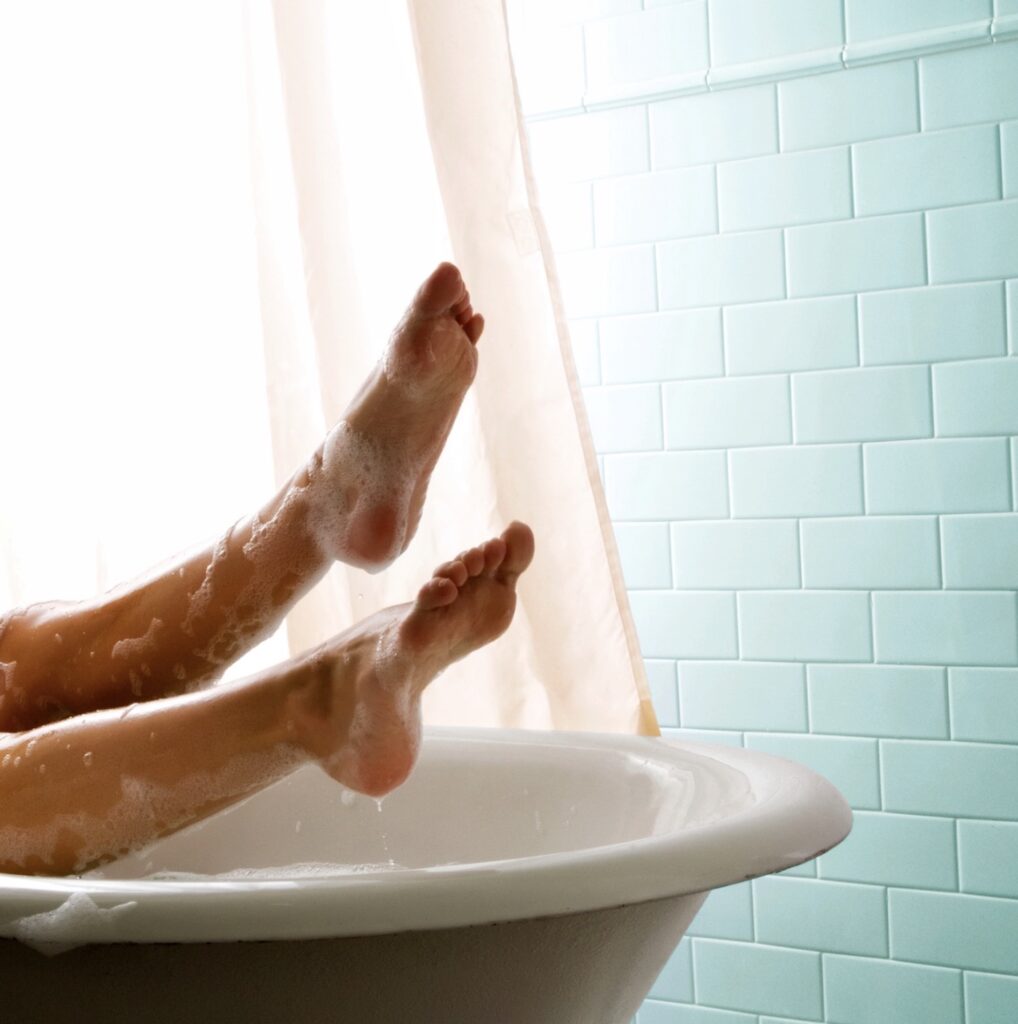 woman sitting in bathtub with bubbles and blue wall