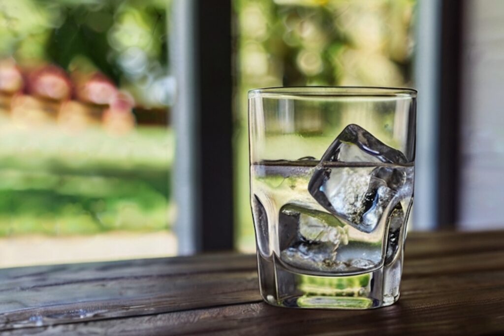 Glass of water with ice sitting near window