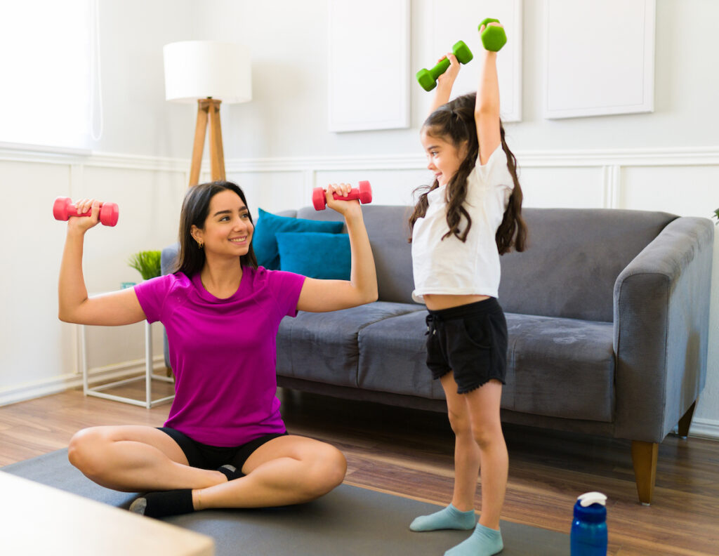 Active young mother lifting weights with daughter for better T1D management