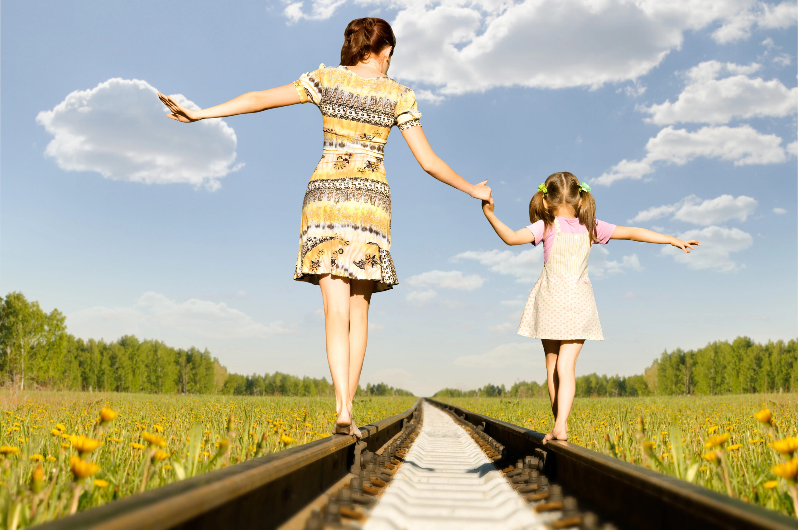 Mother and daughter balancing on railroad in nature