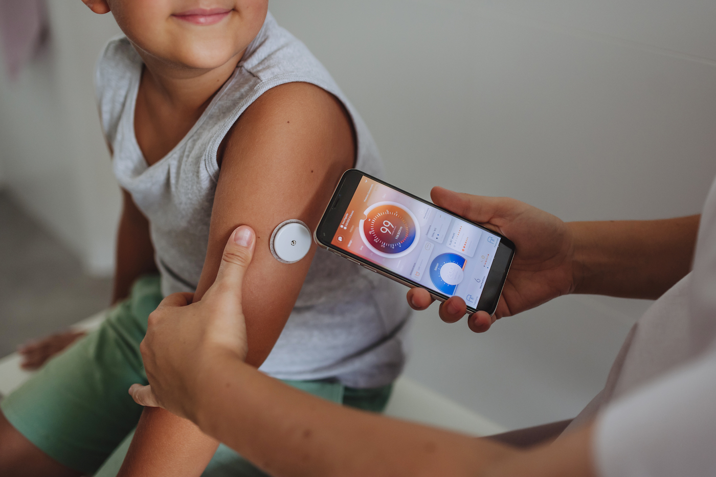 Young boy with type 1 diabetes caregiver having his blood sugar checked with a continuous glucose monitor