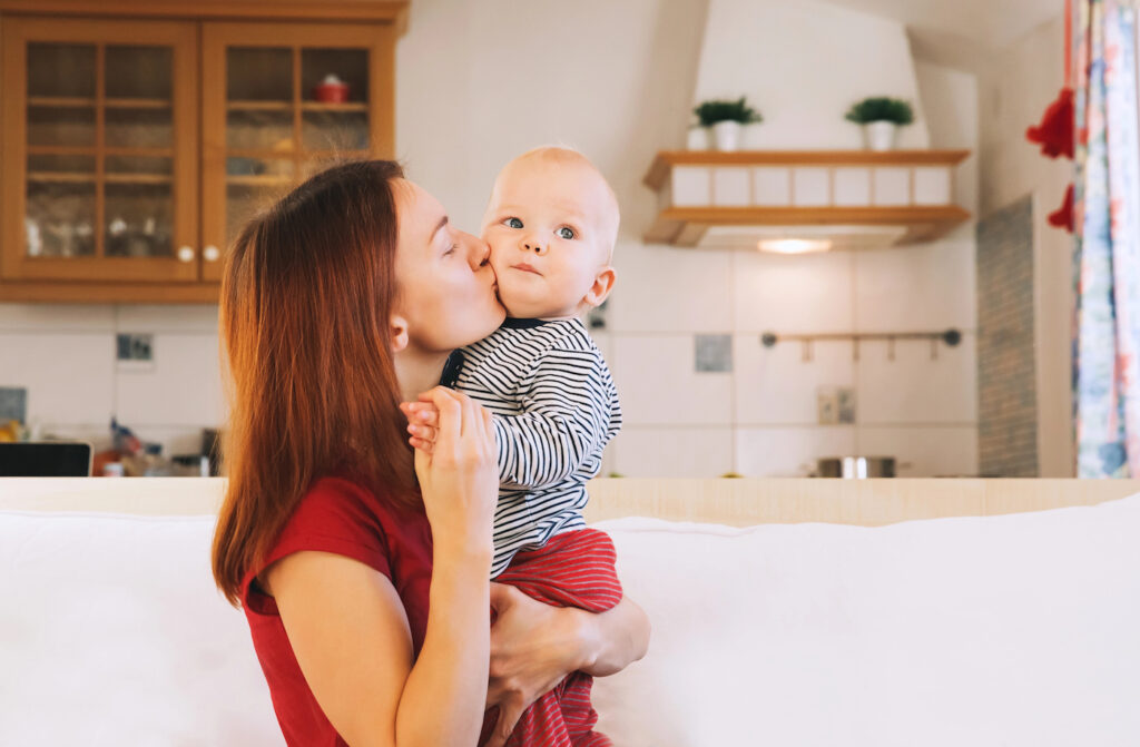 Young type 1 diabetes mom kissing young child in kitchen