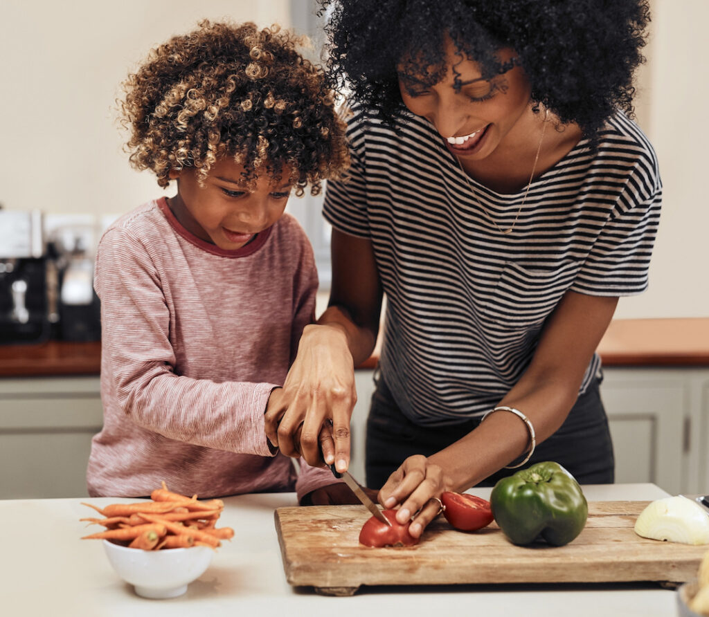 A T1D mom chopping vegetables in the kitchen with her young son, symbolizing healthy routines and family connection. Discover 3 essential habits for T1D families to thrive together.