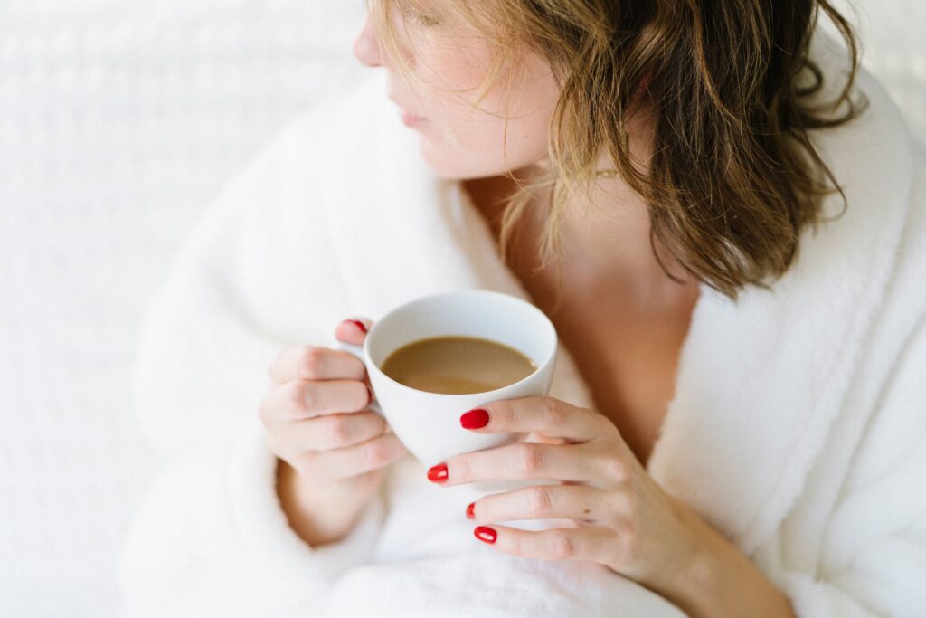 A tired mom wrapped in a cozy white robe, holding a warm mug of coffee close to her chest. A soft, reflective moment captured to represent calm in the chaos. Image for a blog post by Allee Peterson founder of Type Won Coaching™, a National Board Certified Health Coach and fellow T1D spouse.